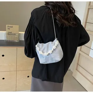 Detalle de bolso bandolera azul claro en forma de nube con asa de perlas y cadena
