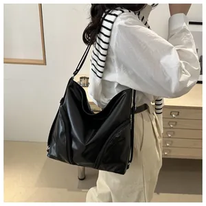 Detail view of black soft PU leather tote bag worn by a model in a cozy indoor setting