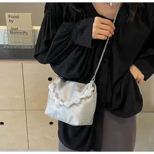 Detalle del bolso bandolera plateado metalizado con cuentas grandes y cadena de metal