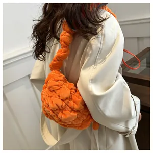 Detail of bright orange plush shoulder bag showing soft pleated texture and cloud design