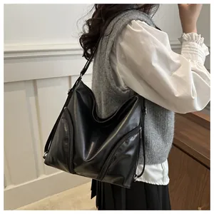 Close-up of black PU leather hobo bag with decorative side zippers on a shoulder strap