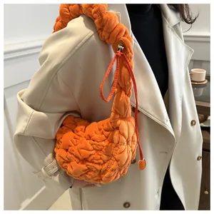 Detail view of the orange pleated shoulder bag featuring a stylish quilted cloud texture