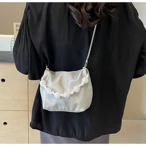 Bolso bandolera plateado metalizado con grandes cuentas blancas sobre ropa negra