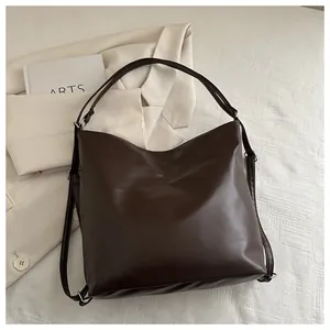 Flat lay of a large dark brown matte leather tote bag styled with a beige blazer