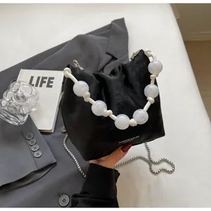 Detalle de bolso saco negro mate con cordón y asa de perlas con efecto mármol