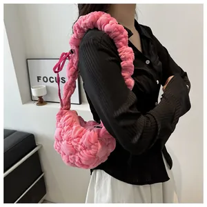 Detail showing pink pleated plush fabric texture and knotted strap of the cloud bag
