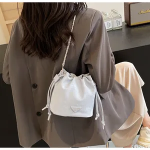 Gros plan du sac seau bleu clair avec bandoulière chaîne porté par un mannequin en veste