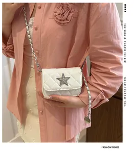 Detail of white quilted crossbody bag with star rhinestone buckle and chain strap