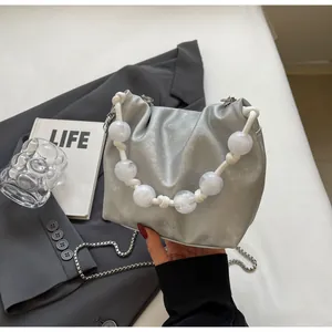 Detalle del bolso saco de satén plateado con cuentas jaspeadas y asa trenzada