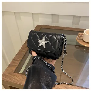 Detailed macro view of a mini black quilted bag with a sparkling rhinestone star motif