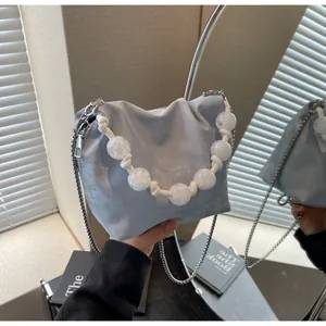 Detalle del bolso de cubo plisado azul claro con asa de cuentas y cadena metálica fina