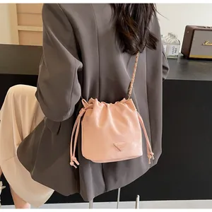 Détail du sac seau rose avec cordon de serrage, bandoulière chaîne et plaque décorative