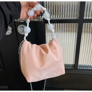 Detalle del bolso de cuero rosa mate con asa de cuentas blancas y cadena plateada fina