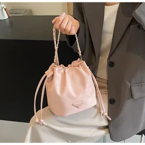 Détail du sac seau rose clair avec cordon de serrage, chaîne dorée et logo