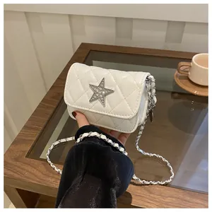 Detail of white quilted crossbody bag with star emblem and silver chain strap
