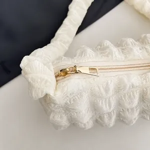 Détail d'une fermeture éclair dorée sur un sac à bandoulière blanc à texture gaufrée