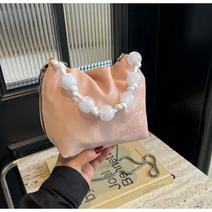 Detalle de bolso de mano rosa plisado con asa de cuentas y correa de cadena