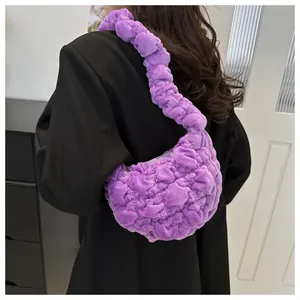 Detail of purple plush cloud bag with quilted pleats worn over a black blazer