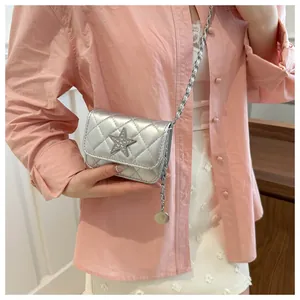 Detail of silver quilted crossbody bag with rhinestone star and metal chain strap