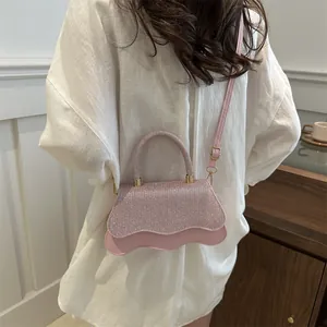 Sparkly pink mini crossbody bag with rhinestone finish and wavy edge on white shirt