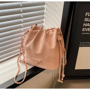 Détail du sac seau rose à cordon avec bandoulière en chaîne dorée et plaque triangulaire