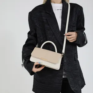 Sac à main chic crème avec rabat tissé et détail doré, porté par un mannequin