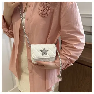 Detail of white quilted crossbody bag with sequined star and chain strap on model