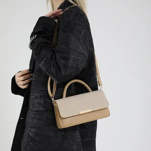 Sac bandoulière kaki avec rabat tressé et boucle dorée sur modèle en manteau noir