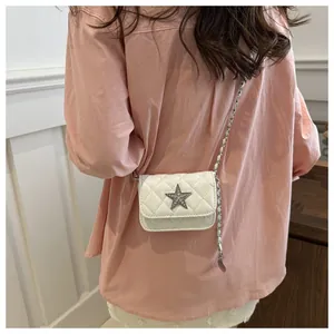 Detail of white quilted mini crossbody bag with star-shaped metal ornament and chain strap