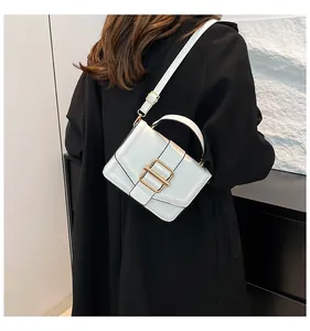 Side view of white rectangular crossbody bag with gold buckle on a black coat