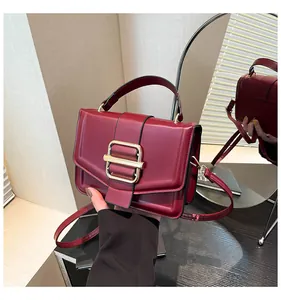 Detailansicht einer weinroten Vintage-Handtasche mit quadratischem goldenem Metallschloss
