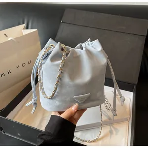 Détail du sac seau bleu clair avec bandoulière chaîne dorée et cordon de serrage