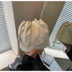 Détail du sac seau blanc cassé avec cordon de serrage, chaîne dorée et logo mode