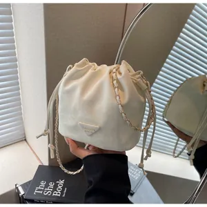 Détail du sac seau blanc à cordon avec étiquette mode et bandoulière en chaîne