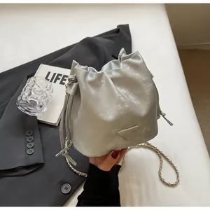 Détail du sac seau argenté avec fermeture à cordon et bandoulière en chaîne