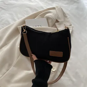 Fashionable black corduroy shoulder bag with brown leather trim in a minimalist style