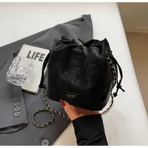 Détail du sac seau noir en cuir PU avec bandoulière chaîne et logo en métal triangle