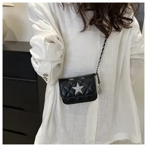 Detail of a black quilted crossbody bag with a rhinestone star and leather chain strap
