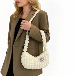 Sac bandoulière blanc à texture bulles et bandoulière plissée porté par un mannequin