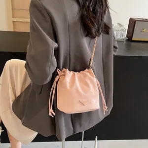 Sac seau rose à cordon avec bandoulière chaîne et pompons, style porté croisé