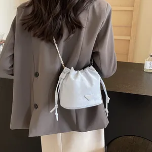 Sac seau bleu clair à cordon avec bandoulière chaîne et logo triangle sur costume