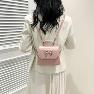 Pink mini leather backpack with silver metal bow accent shown on a model