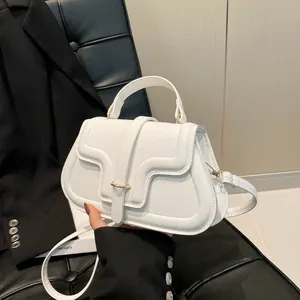 White lychee texture handbag with gold buckle and shoulder strap in a stylish setting
