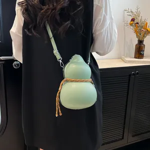 Light green gourd-shaped crossbody bag with decorative rope on a stylish model back view