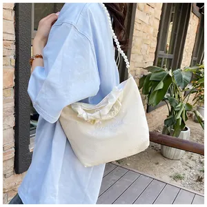 Detail of cream hand bag with GoodLuck embroidery and elegant pearl chain strap