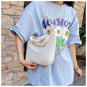 Close-up of white woven handbag featuring blue Goodluck embroidery and pearl chain strap