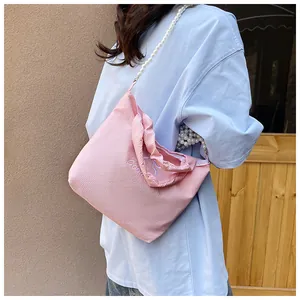 Detail of pink fabric handbag with faux pearl strap and embroidered Good lettering