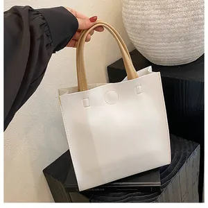 Close-up of white leather tote bag with contrasting tan handles and stitch detail
