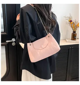 Detail einer rosa glänzenden Umhängetasche mit Goldkette, von einem Model getragen