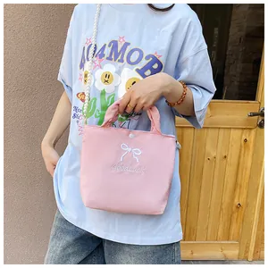 Detail of pink bow handbag featuring GoodLuck embroidery and faux pearl chain strap